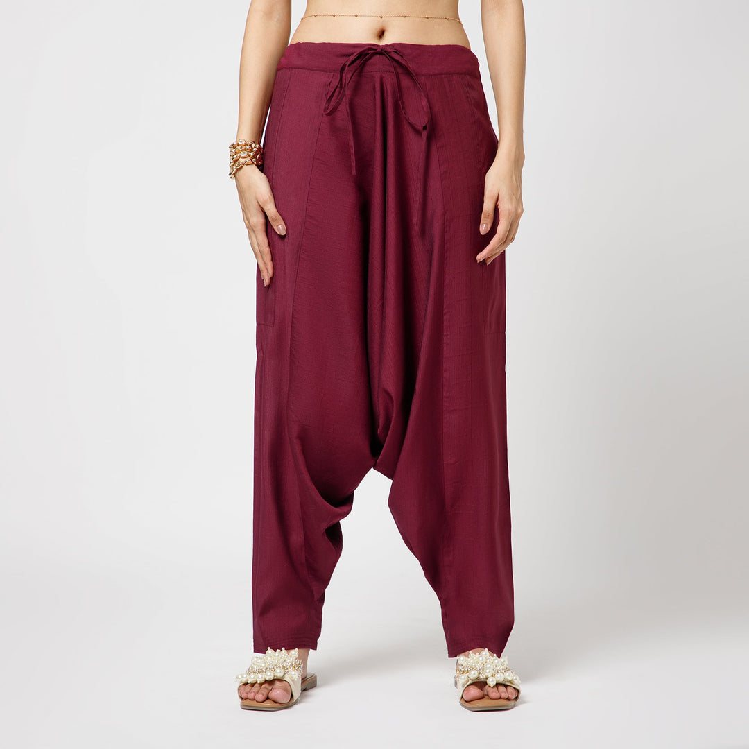 Maroon harem pants worn by a person on a white background